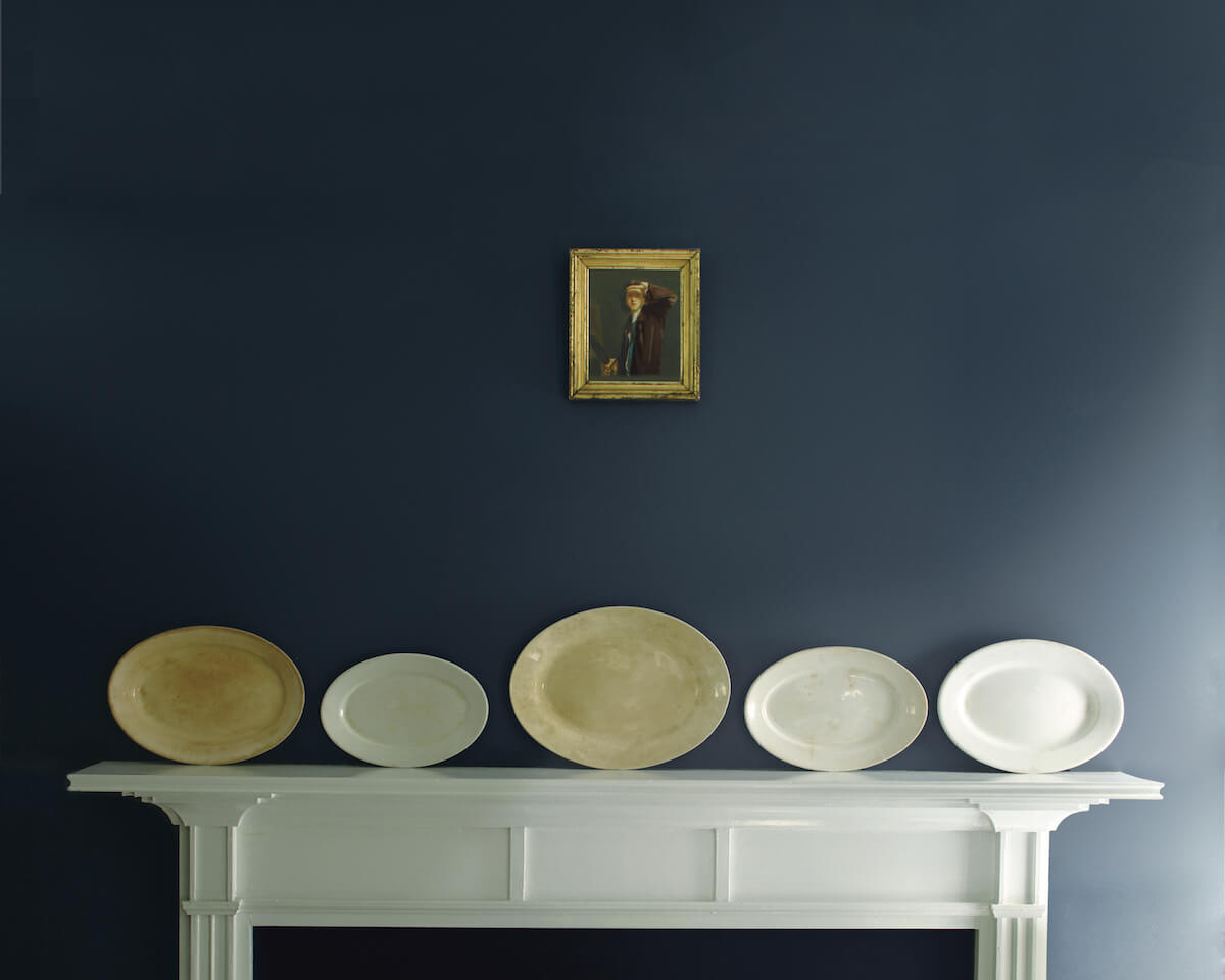 Deep blue accent wall with decorative plates against white mantel