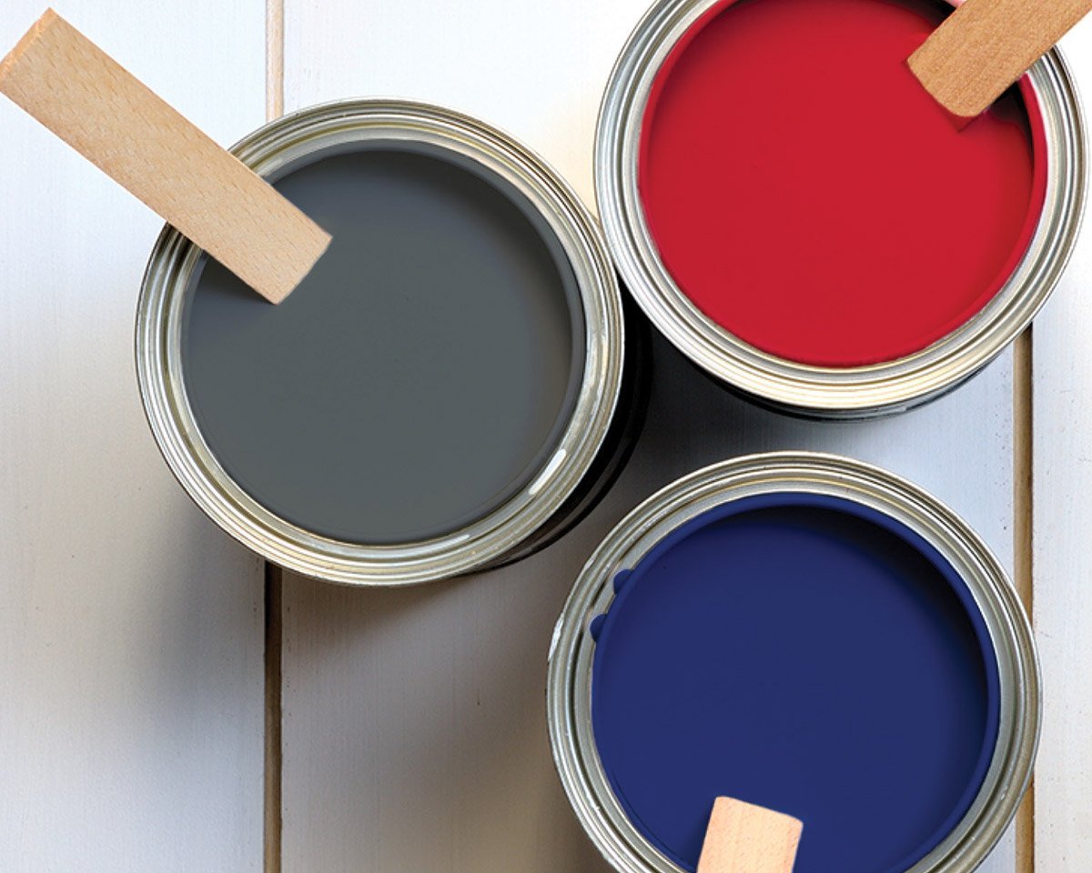 Top down view of three paint buckets with grey red and blue paint in them